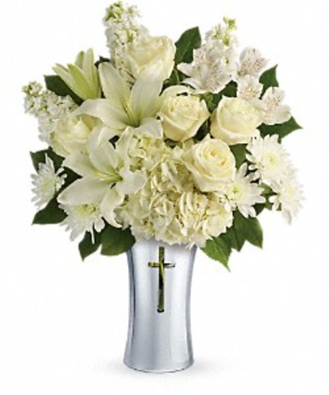 Silver cross vase filled with white hydrangea, lilies and greenery