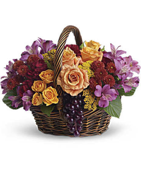 A dark, handled basket delivers a mix of orange roses, maroon carnations, purple alstroemeria, burgundy button mums and yellow yarrow