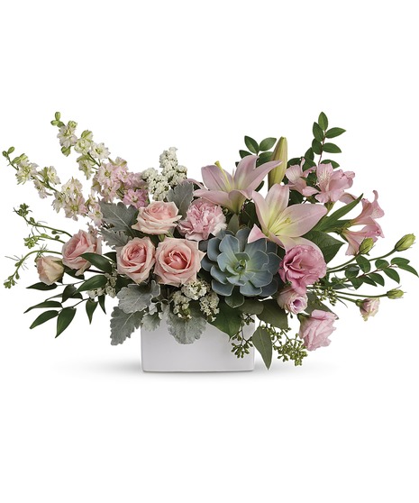 Pale pink and green arrangement presented in a white square vase
