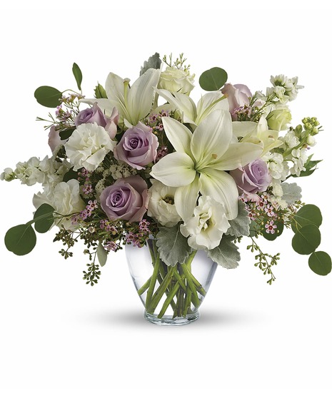 Bouquet of lavender & cream flowers in a clear glass vase